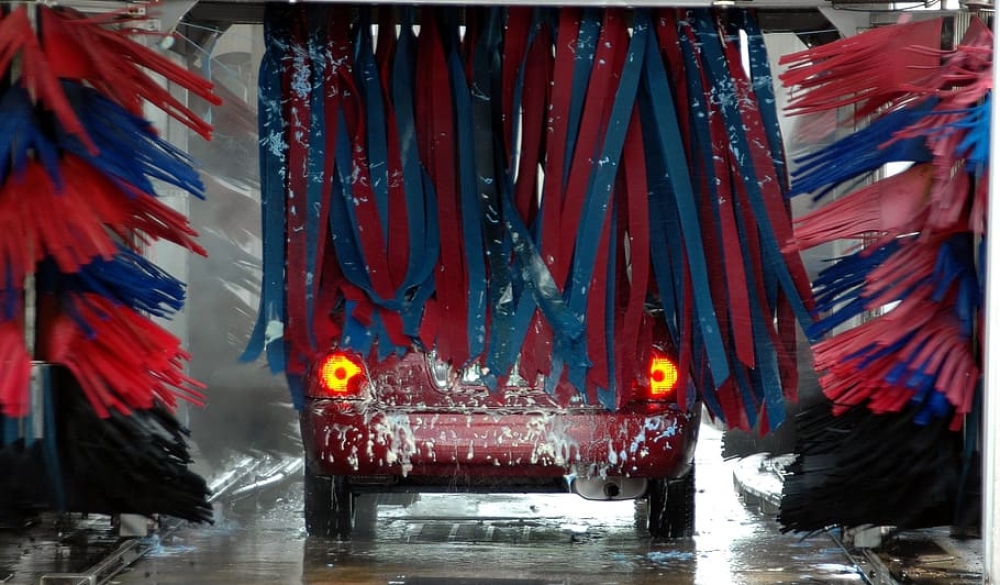 In de carwash liggen knokkende mannen op de grond, daarna vliegen er kogels rond