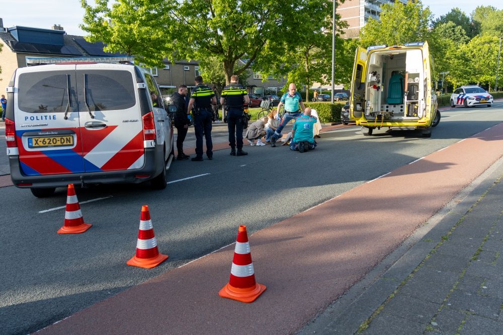 Vrouw op fiets en motorrijder botsen op elkaar, vrouw loopt hoofdwond op