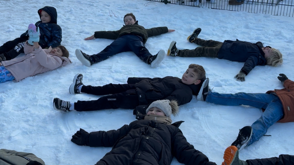 Leerlingen genieten van het witte schoolplein: sneeuwballengevecht en sneeuwengel
